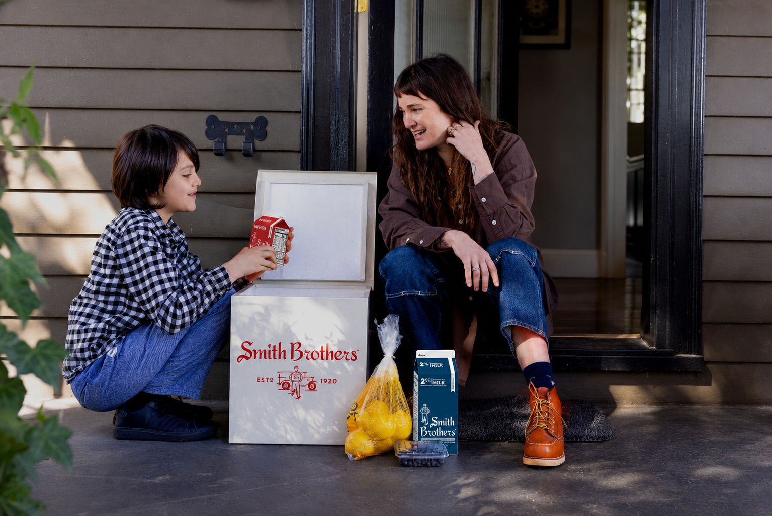 A mother and son on their Portland porch opening a Smith Brothers delivery box